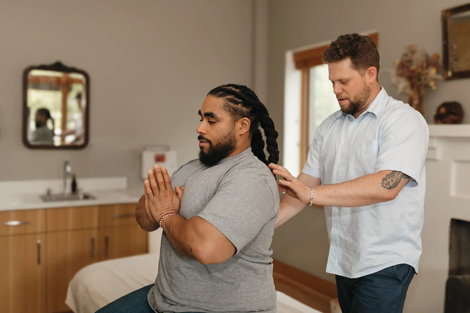 A practitioner checks the shoulders of a patient seated on a treatment table at Mandala Medicine in Portland